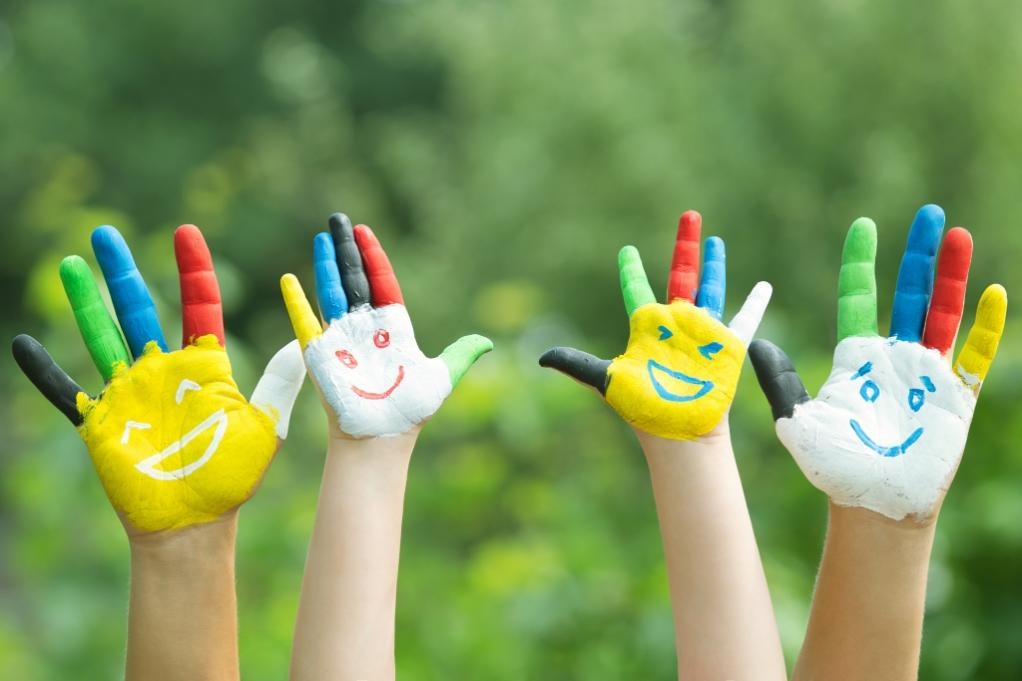 Vier Hände mit bemalt bunten Gesichtern; Bild: istock_Maximkostenko