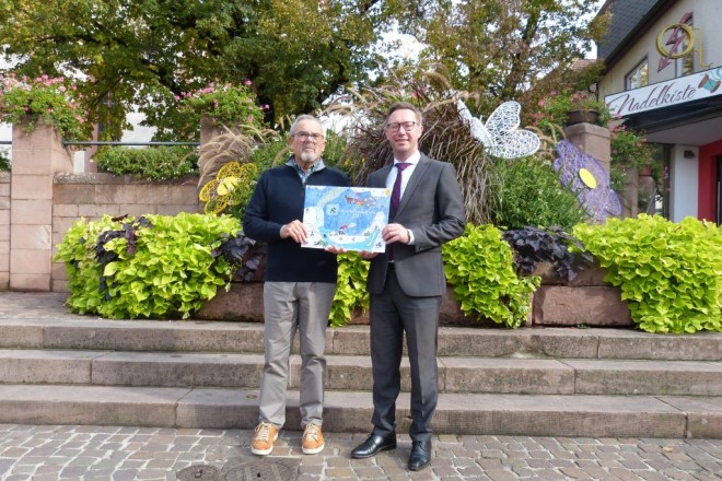 Gerhard Lauth (links) und OB Julian Stipp mit dem Lions Club Adventskalender 2023 (Foto: Stadt Mosbach)